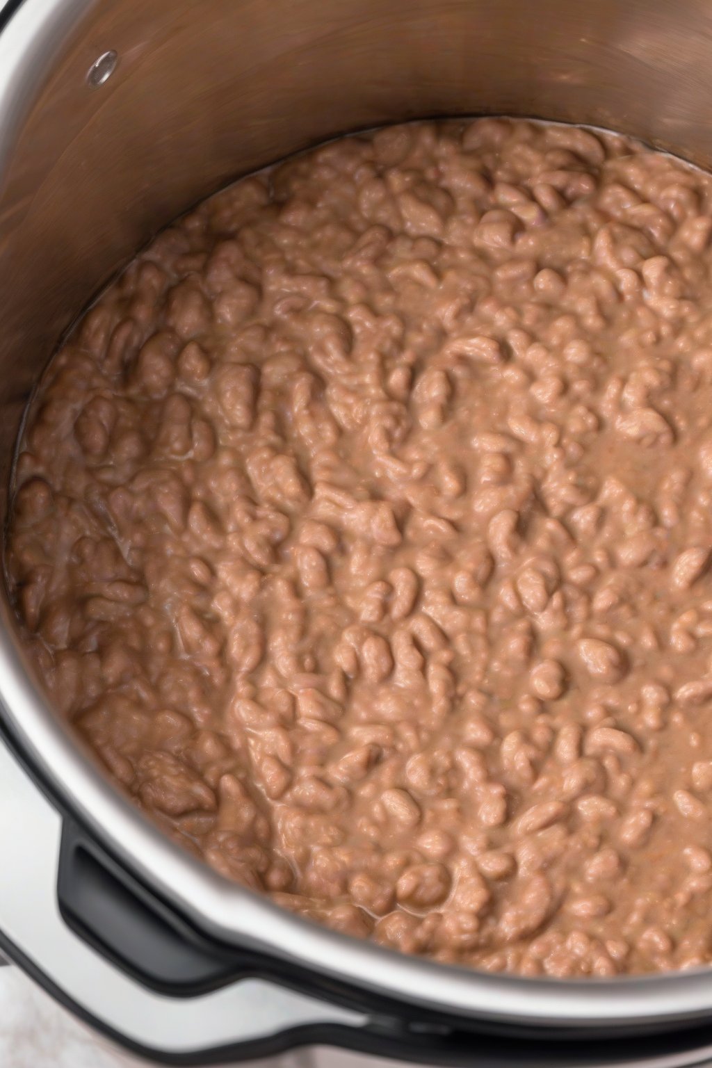 A high-resolution photo of Instant Pot refried beans fresh from the cooker, creamy mound, under soft lighting.